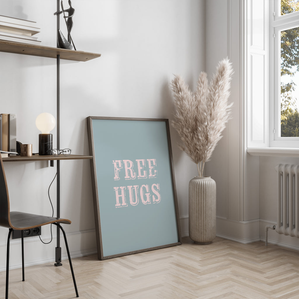 Room interior with a 'FREE HUGS' poster, vase with dried plants, and desk.