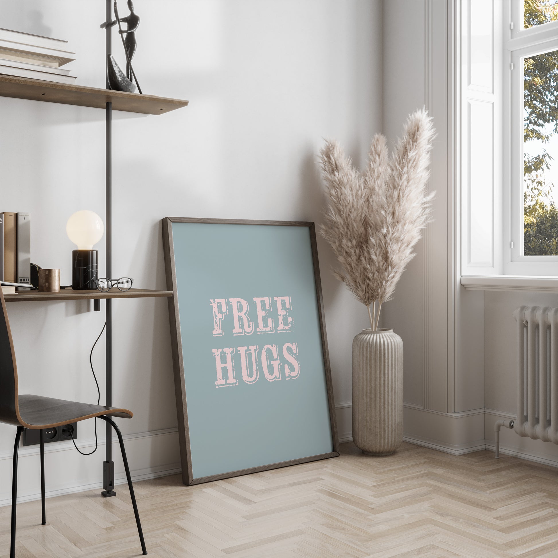 Room interior with a 'FREE HUGS' poster, vase with dried plants, and desk.