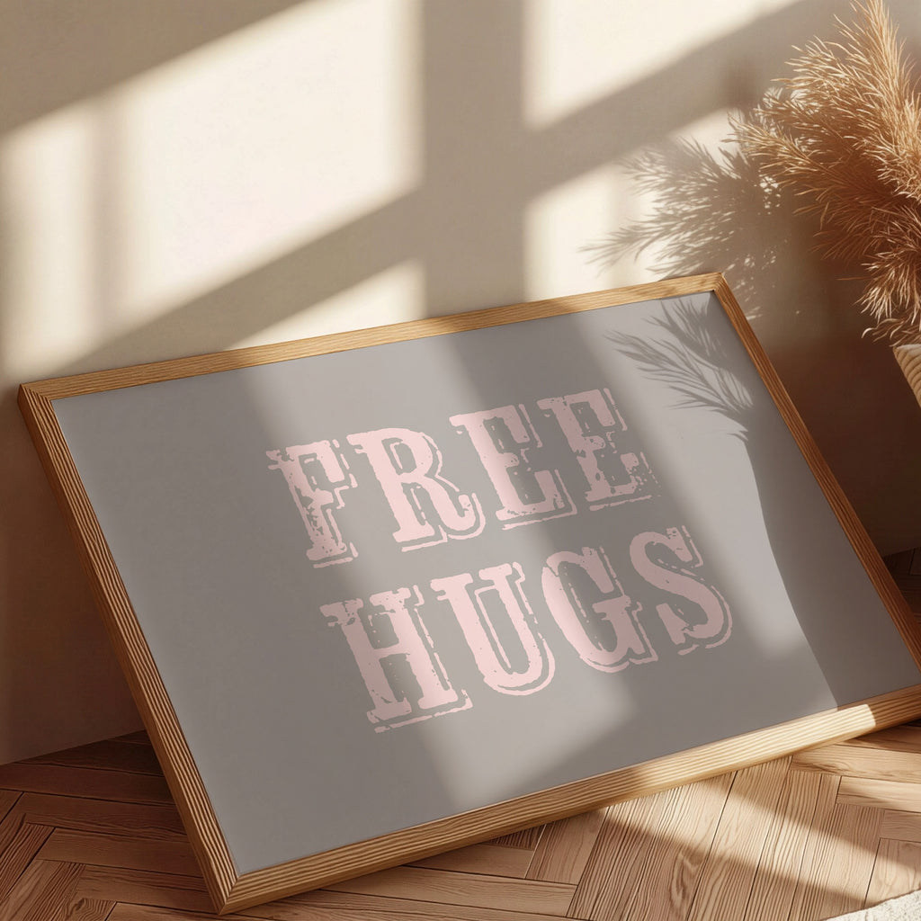 Framed sign with 'FREE HUGS' text on a wooden floor with sunlight casting shadows.