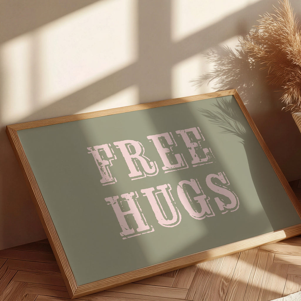 Framed sign with 'FREE HUGS' text on a wooden floor with sunlight casting shadows.