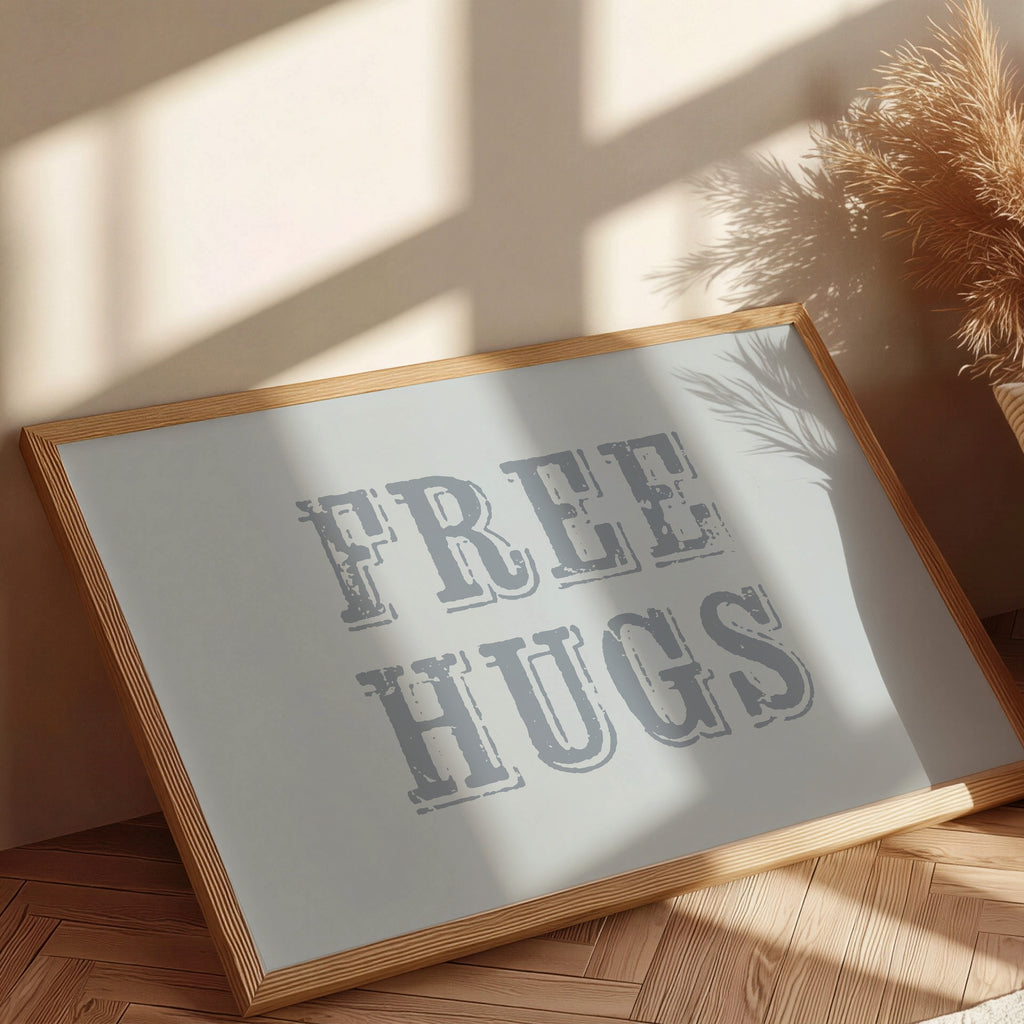 Framed sign with 'FREE HUGS' text on a wooden floor with sunlight casting shadows.