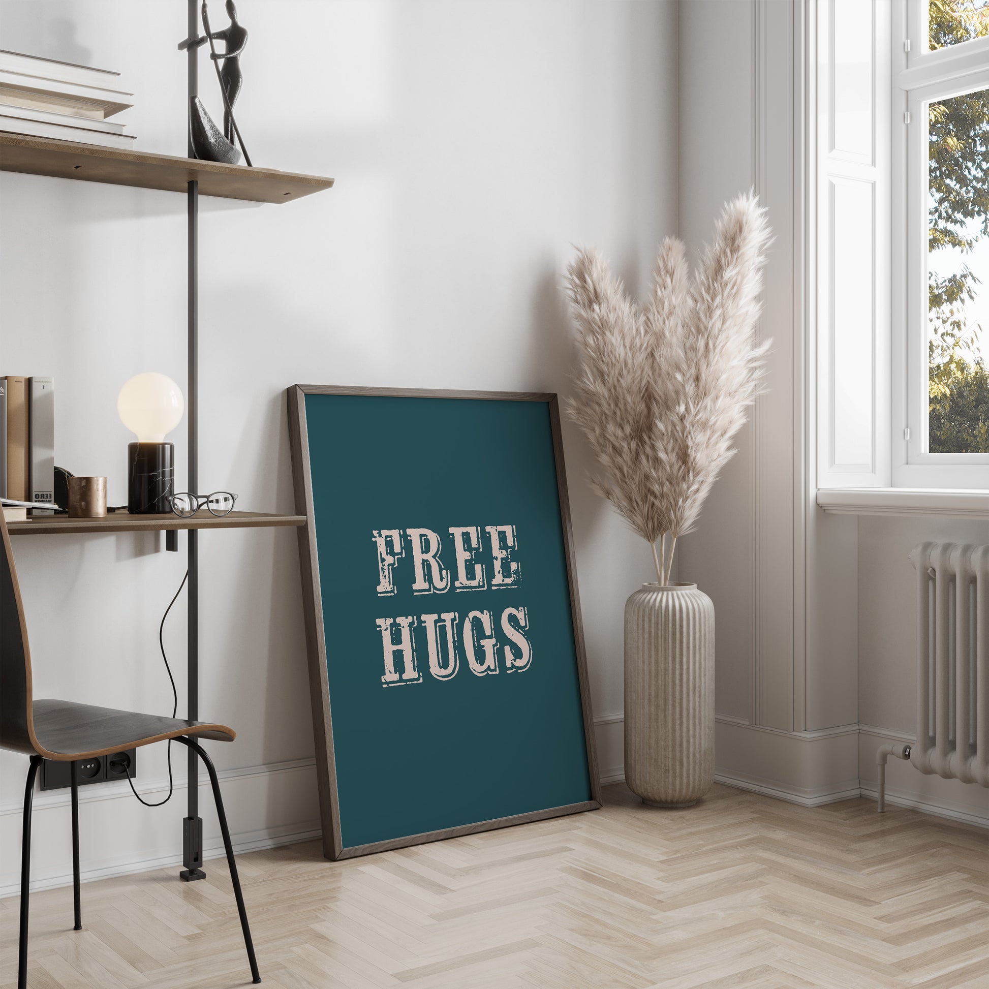 Room interior with a 'FREE HUGS' print leaning on a wall, a vase with dried plants, and a chair.