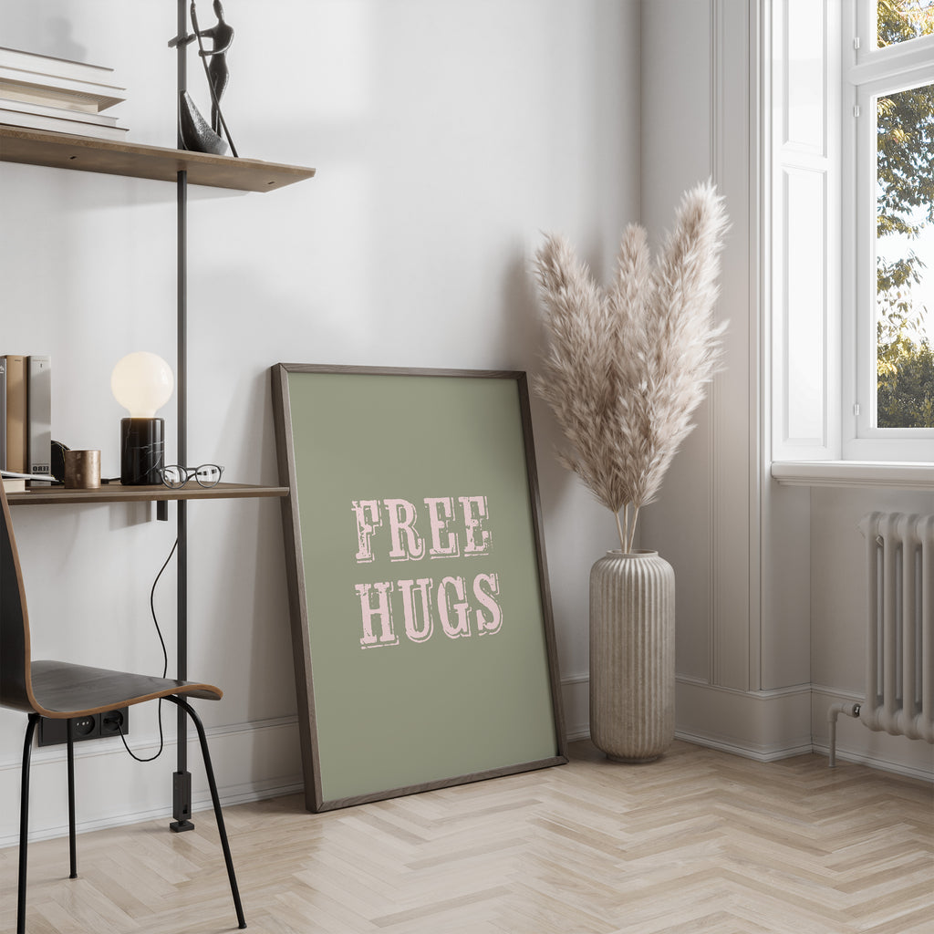 Room interior with a 'FREE HUGS' framed print, a vase with dried plants, and a window.