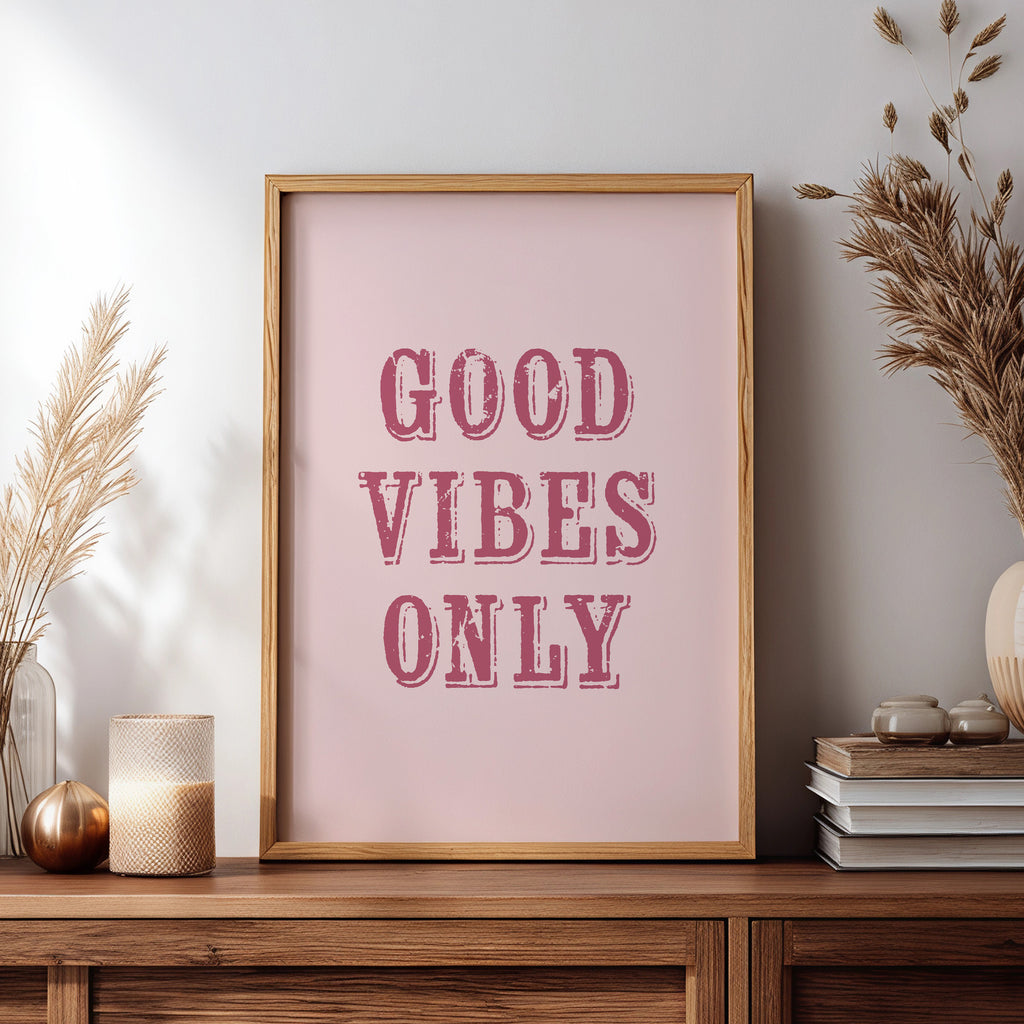 Framed print with 'Good Vibes Only' text on a wooden sideboard with decorative items.