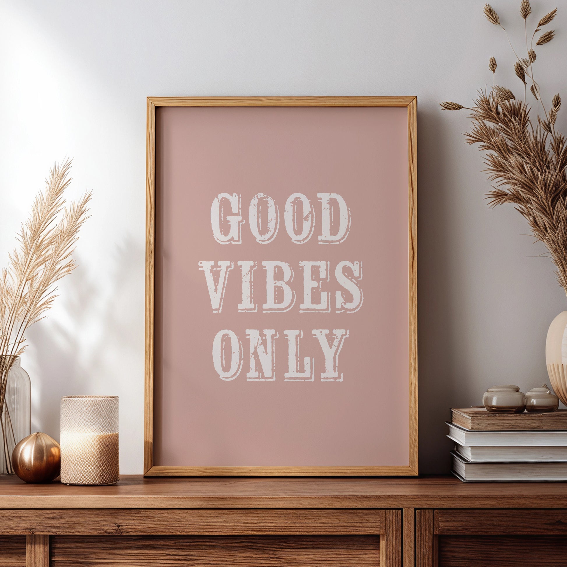 Framed artwork with 'Good Vibes Only' text on a wooden sideboard with decorative items.