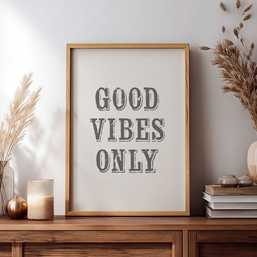 Framed artwork with 'Good Vibes Only' text on a wooden sideboard with decorative items.