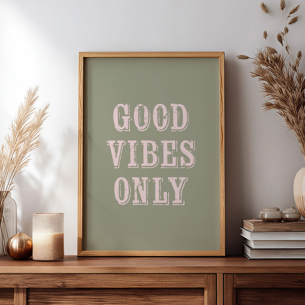 Framed artwork with 'Good Vibes Only' text on a wooden sideboard with decorative items.