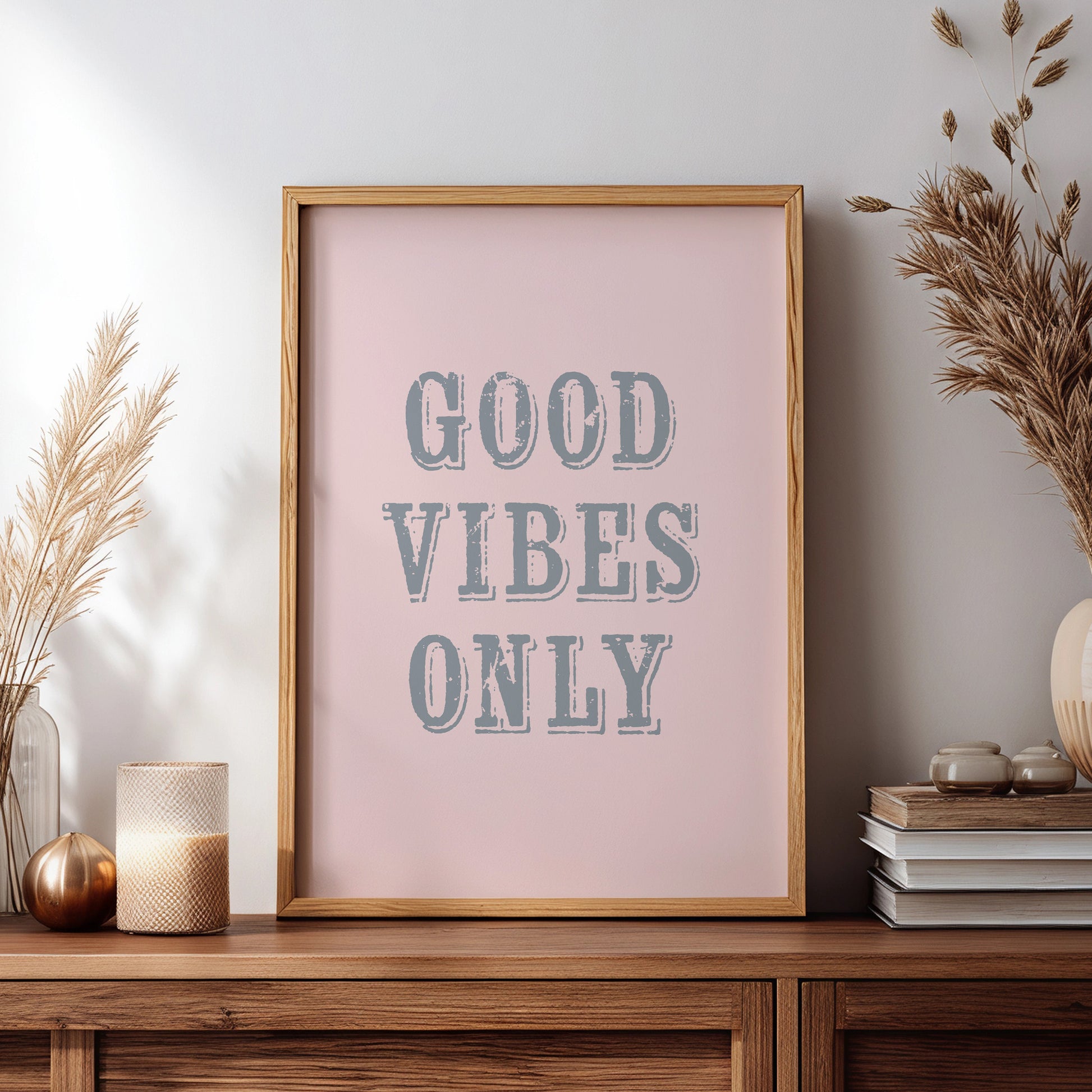 Framed artwork with 'Good Vibes Only' text on a wooden sideboard with decorative items.