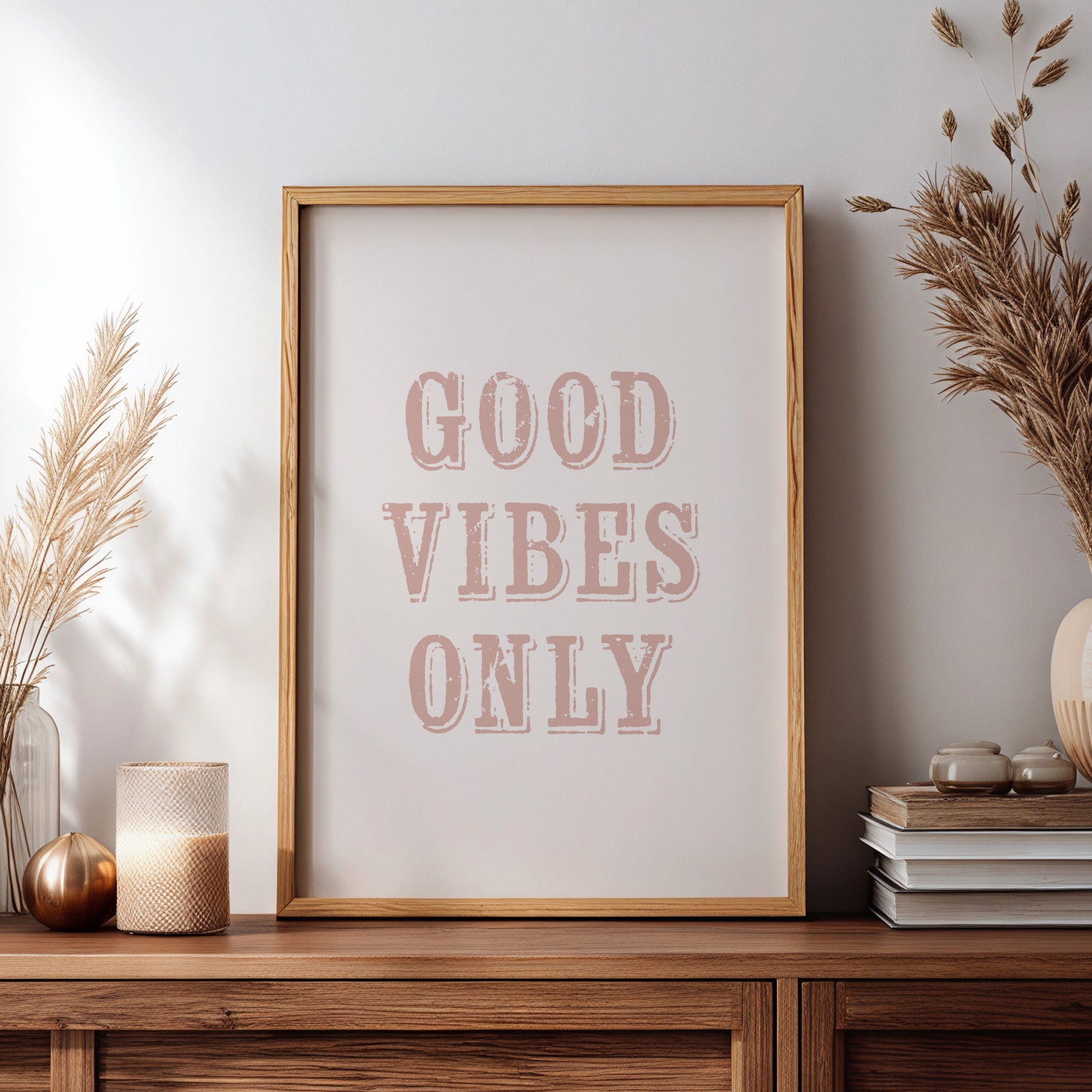Framed print with 'Good Vibes Only' text on a wooden shesideboard with decorative items.