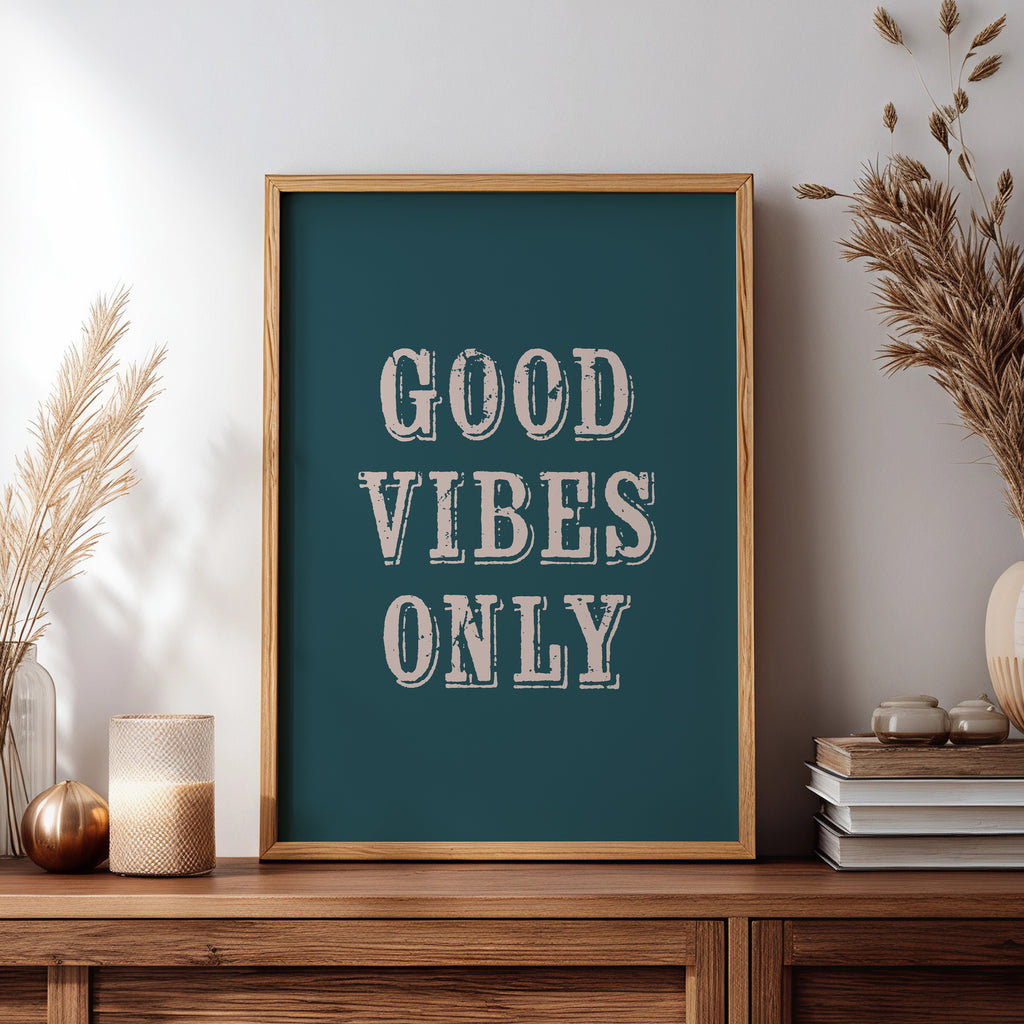 Framed artwork with 'Good Vibes Only' text on a wooden sideboard with decorative items.