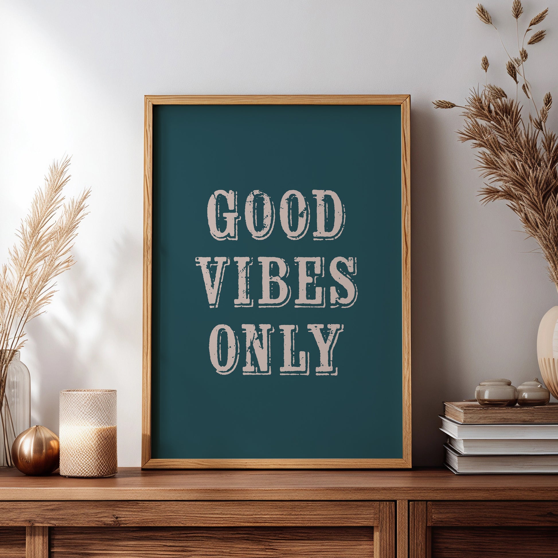 Framed artwork with 'Good Vibes Only' text on a wooden sideboard with decorative items.