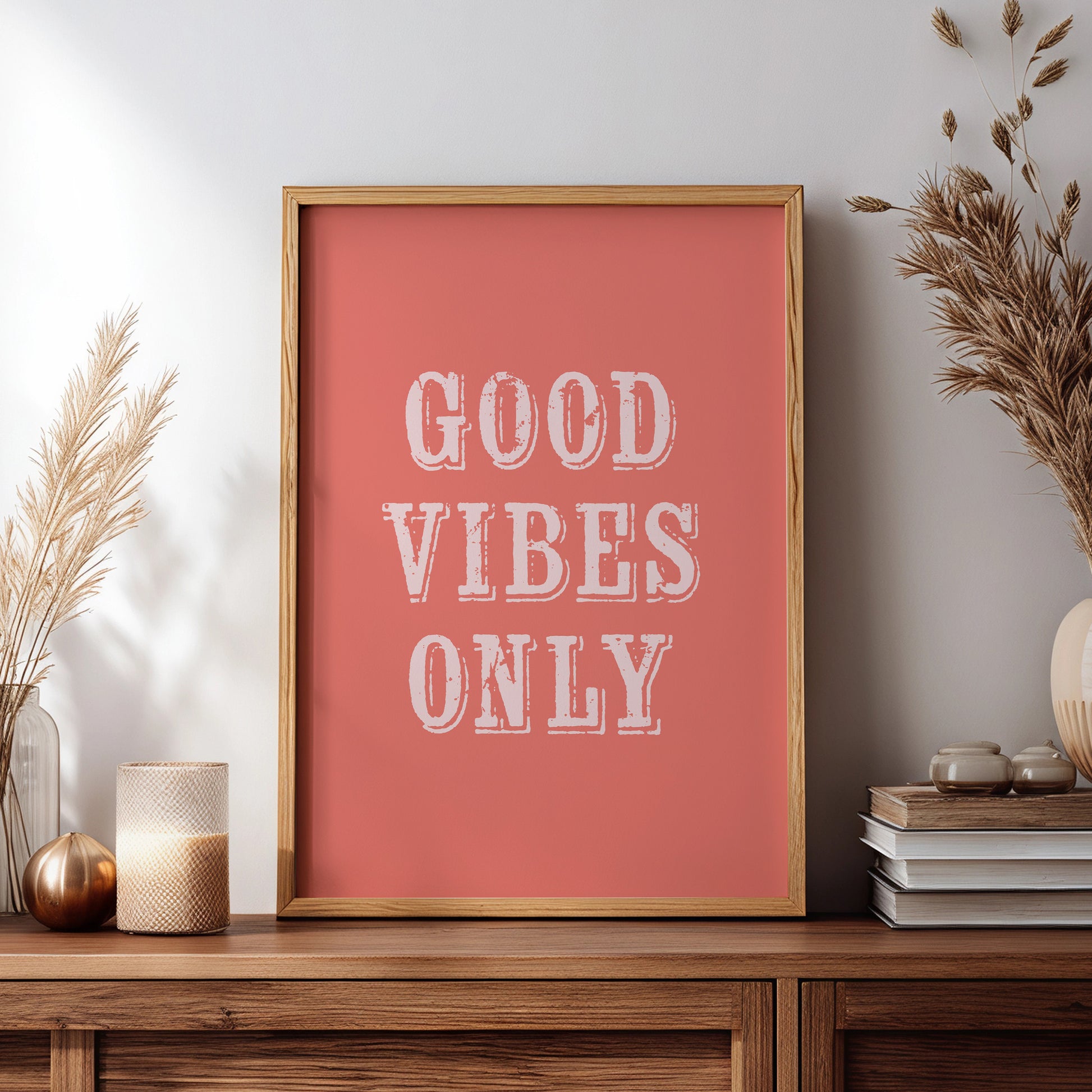 Framed artwork with 'Good Vibes Only' text on a wooden sideboard with decorative items.