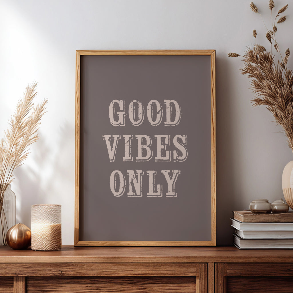 Framed artwork with 'Good Vibes Only' text on a wooden sideboard with decorative items.