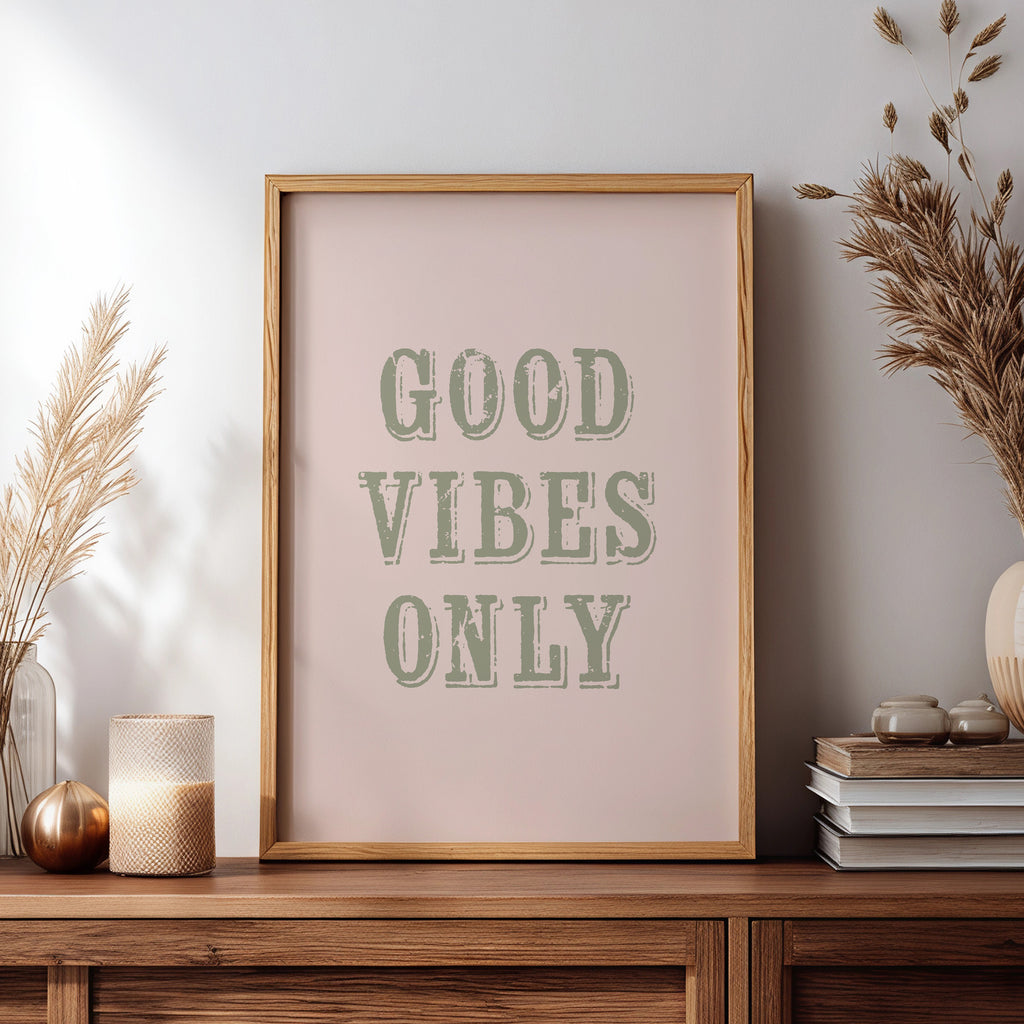 Framed artwork with 'Good Vibes Only' text on a wooden sideboard with decorative items.