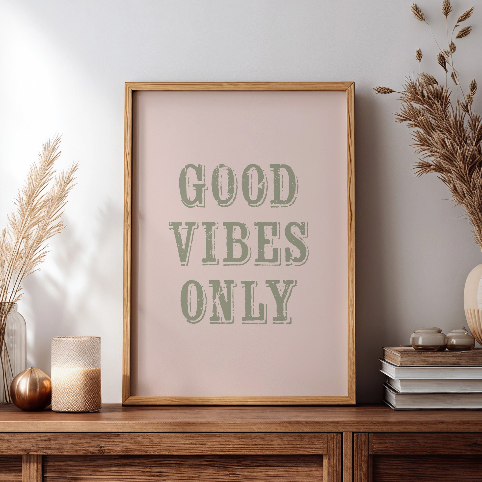 Framed artwork with 'Good Vibes Only' text on a wooden sideboard with decorative items.