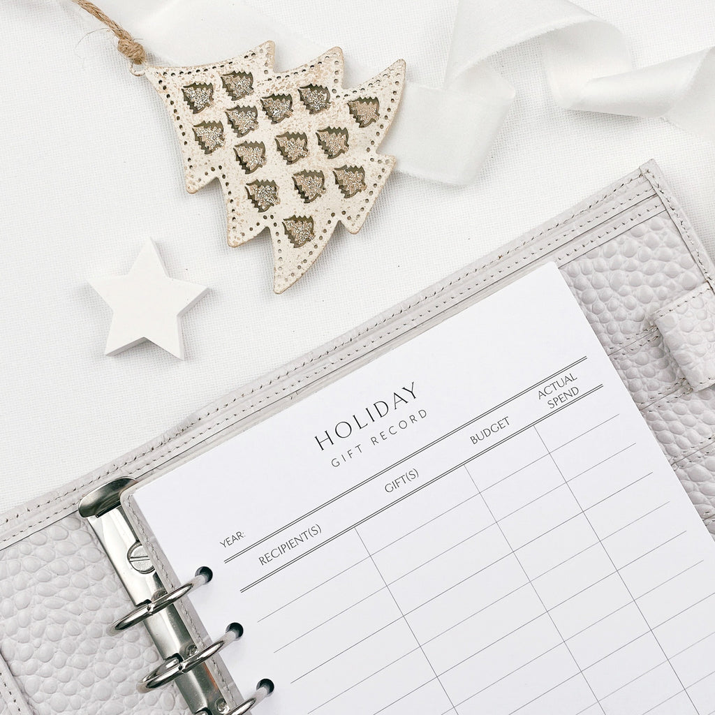 Holiday gift record planner with decorative Christmas tree ornament and star on a white background