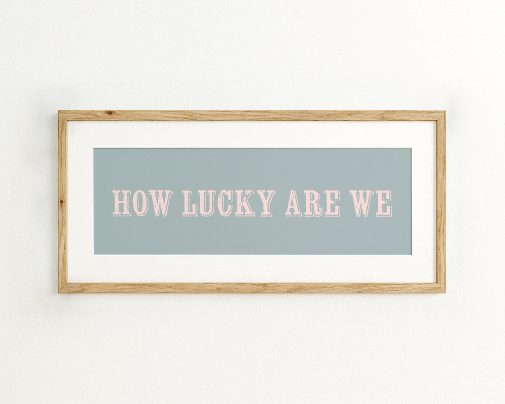 Framed print with 'HOW LUCKY ARE WE' text on a light blue background