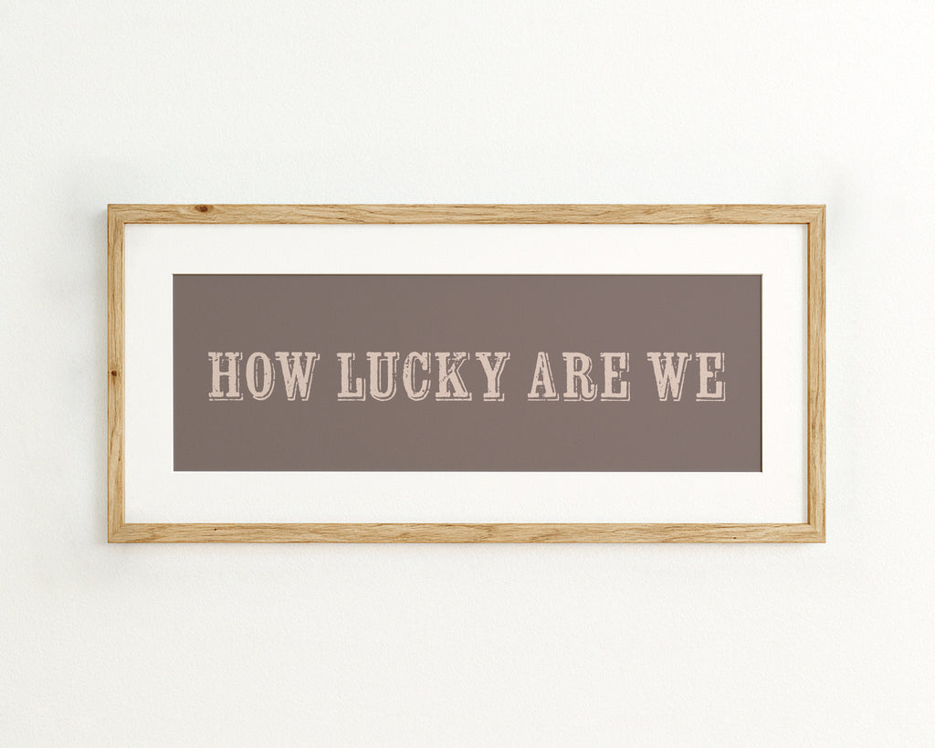 Framed print with 'HOW LUCKY ARE WE' text on a mocha brown background