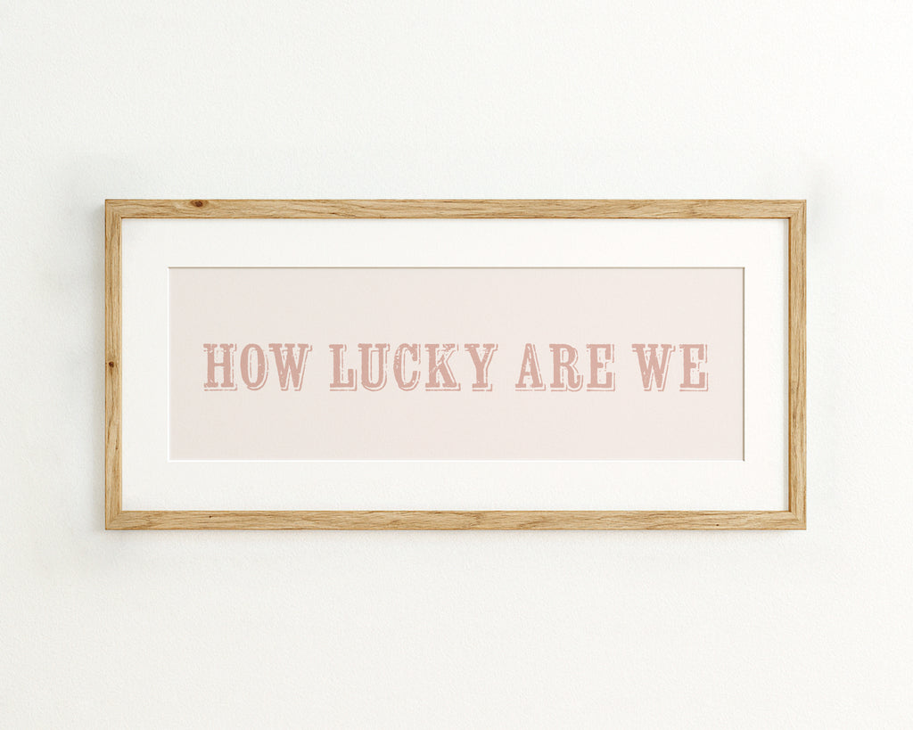 Framed print with 'HOW LUCKY ARE WE' text on a light pink background