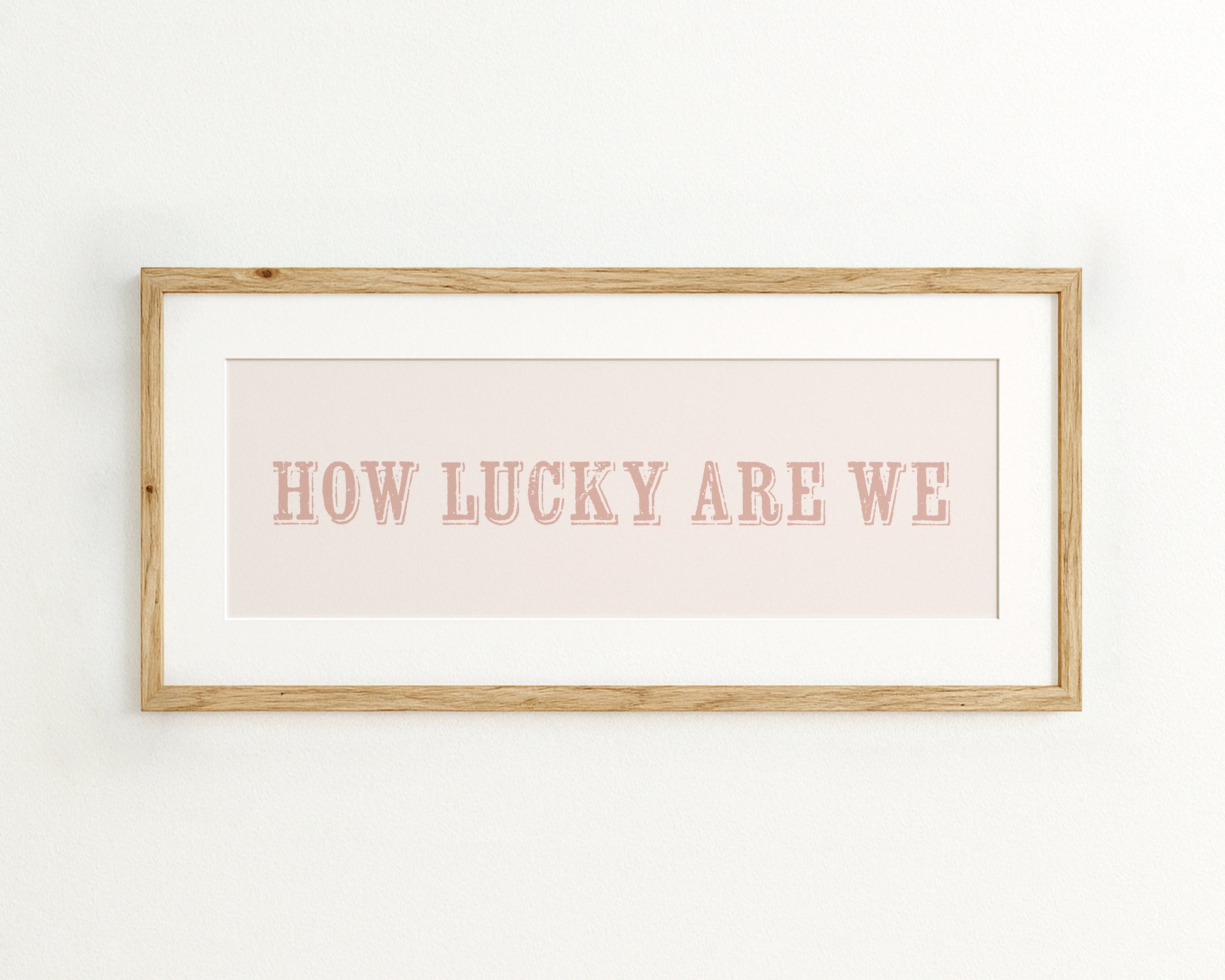 Framed print with 'HOW LUCKY ARE WE' text on a light pink background
