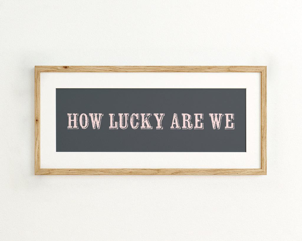 Framed artwork with 'HOW LUCKY ARE WE' text on a dark blue background
