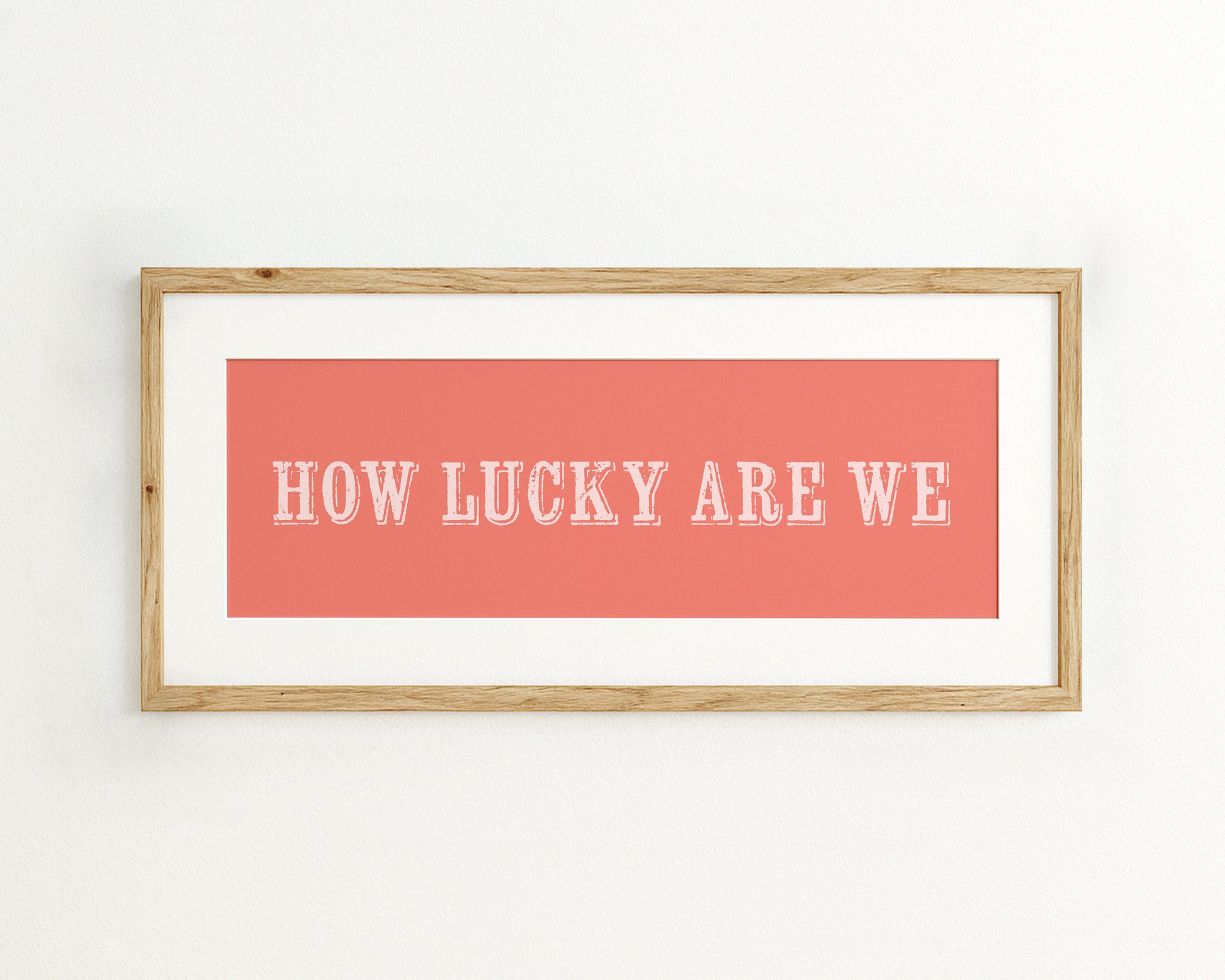 Framed print with 'HOW LUCKY ARE WE' text on a coral background