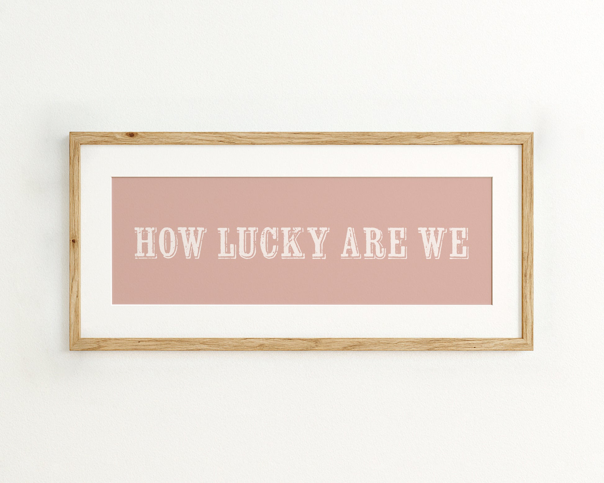 Framed print with 'HOW LUCKY ARE WE' text on a pink background