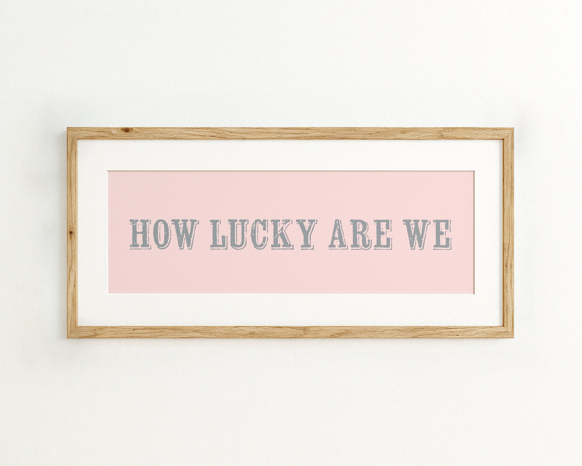 Framed print with 'HOW LUCKY ARE WE' text on a pink background