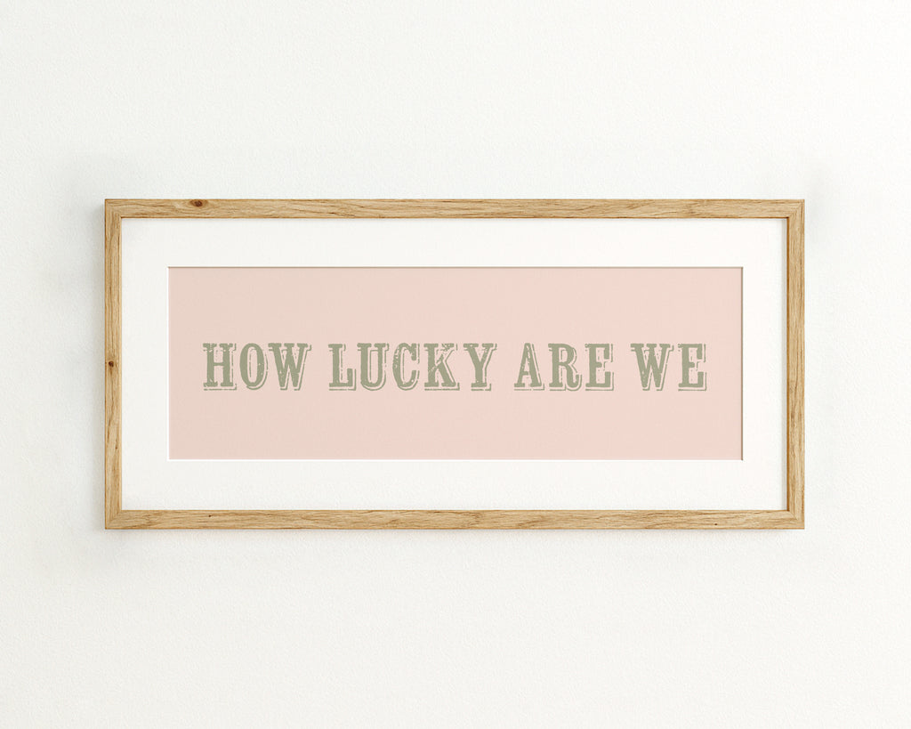 Framed print with 'HOW LUCKY ARE WE' text on a light pink background