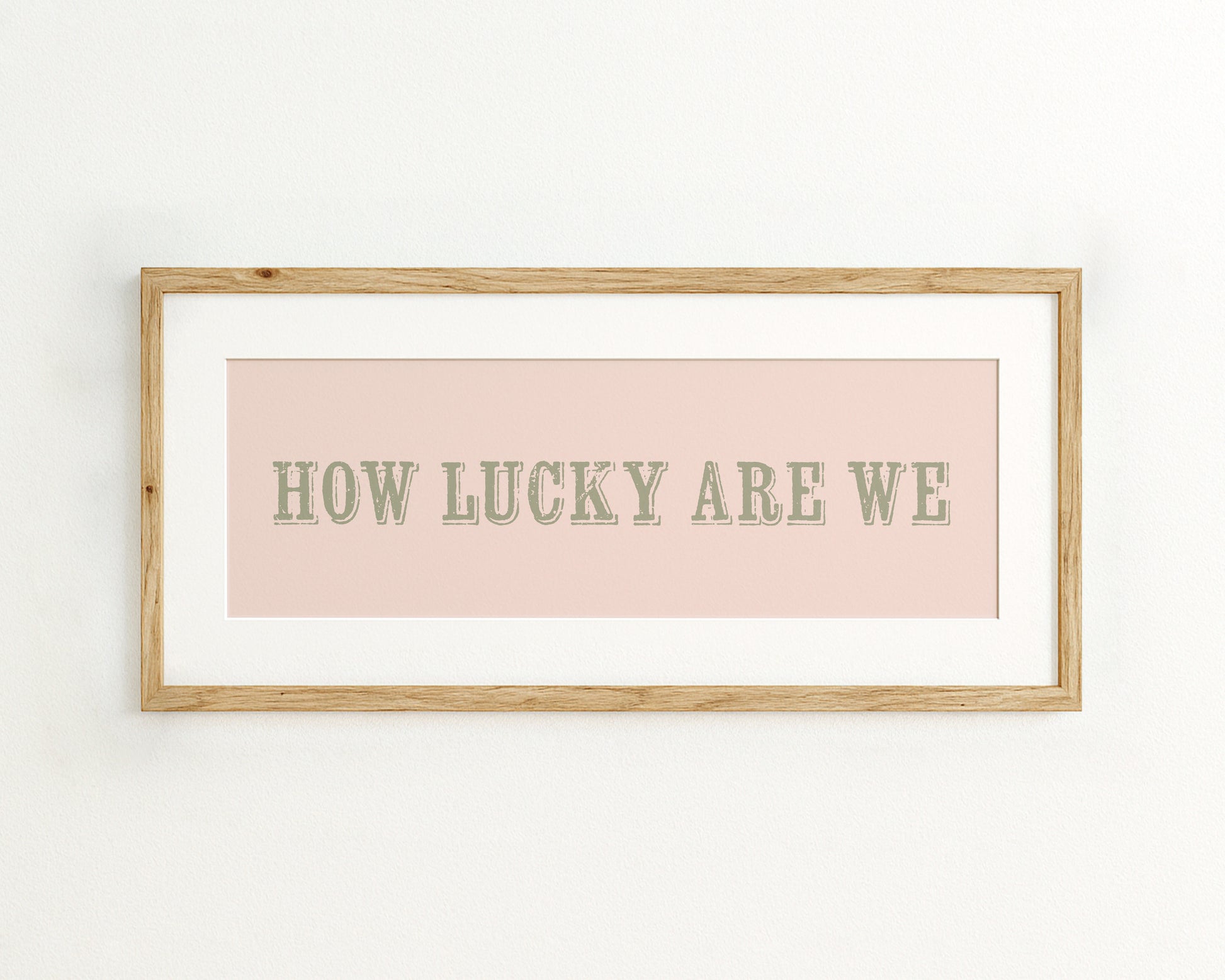 Framed print with 'HOW LUCKY ARE WE' text on a light pink background
