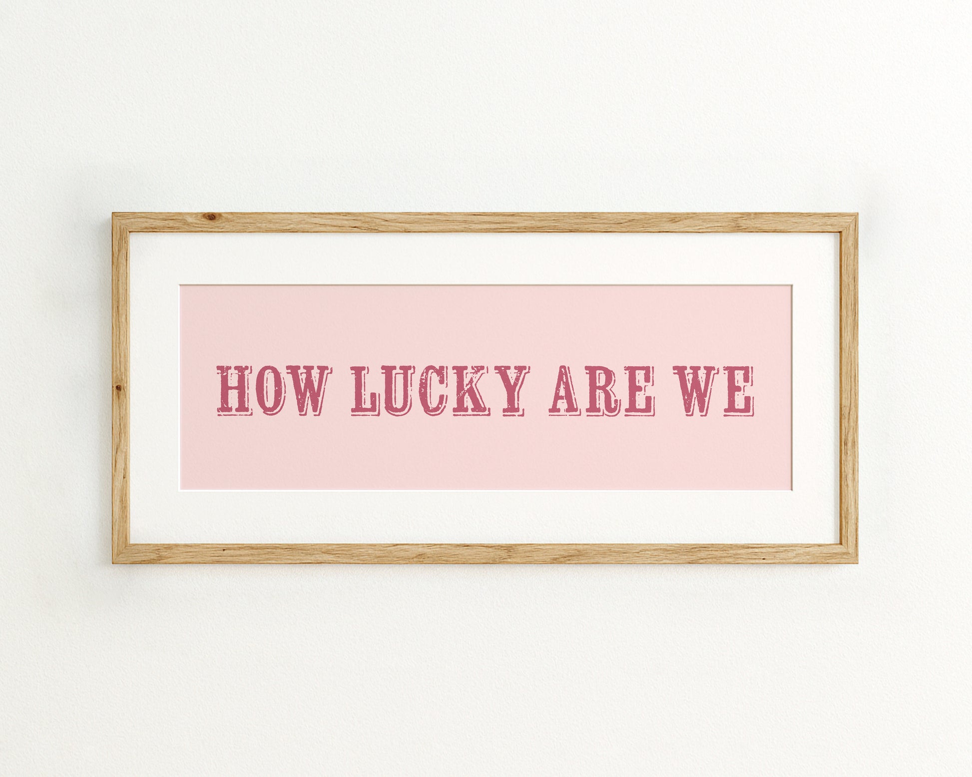 Framed print with 'HOW LUCKY ARE WE' text on a pink background