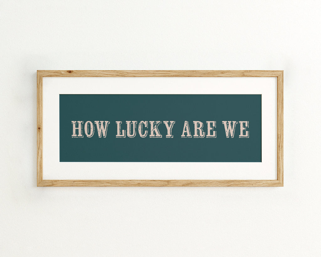 Framed print with 'HOW LUCKY ARE WE' text on a teal background