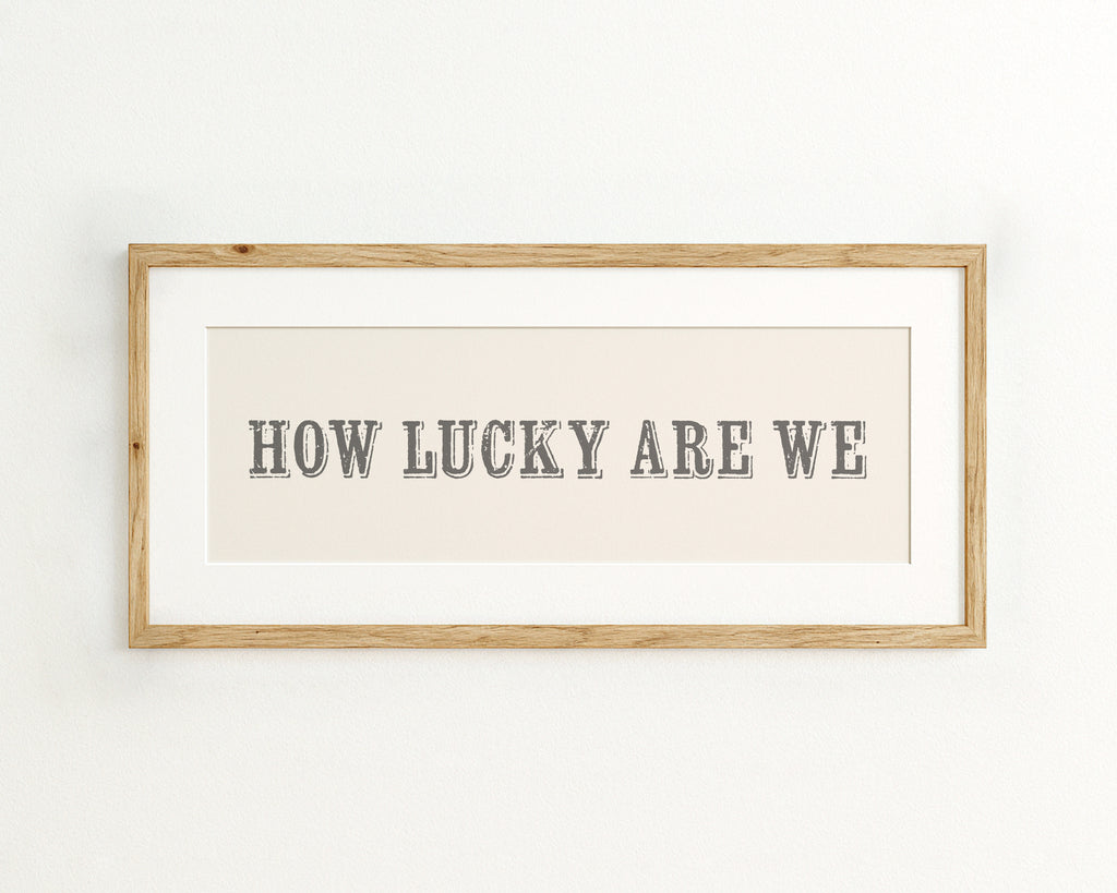 Framed print with 'HOW LUCKY ARE WE' text on a cream background
