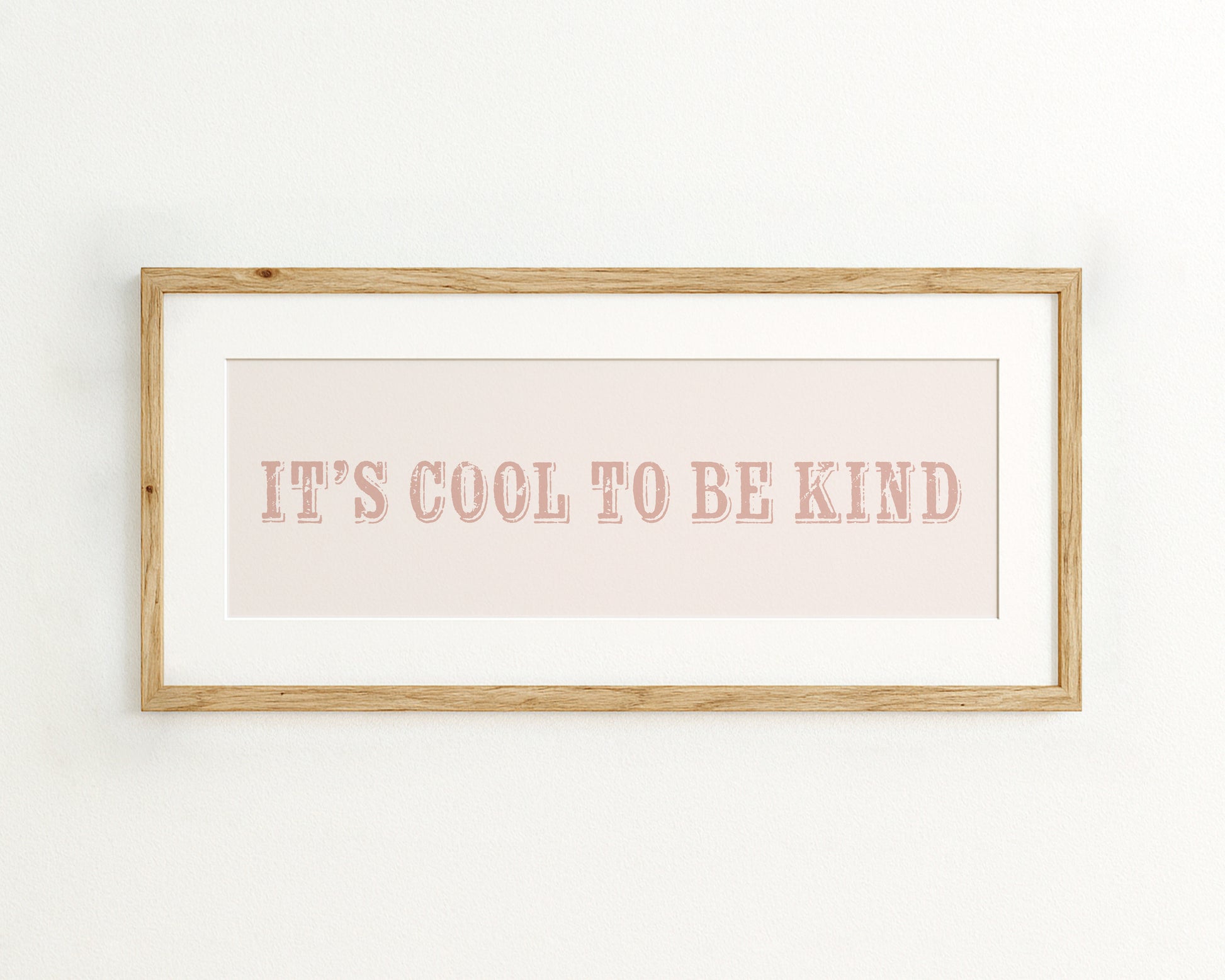 Framed print with 'It's cool to be kind' text on a light pink background
