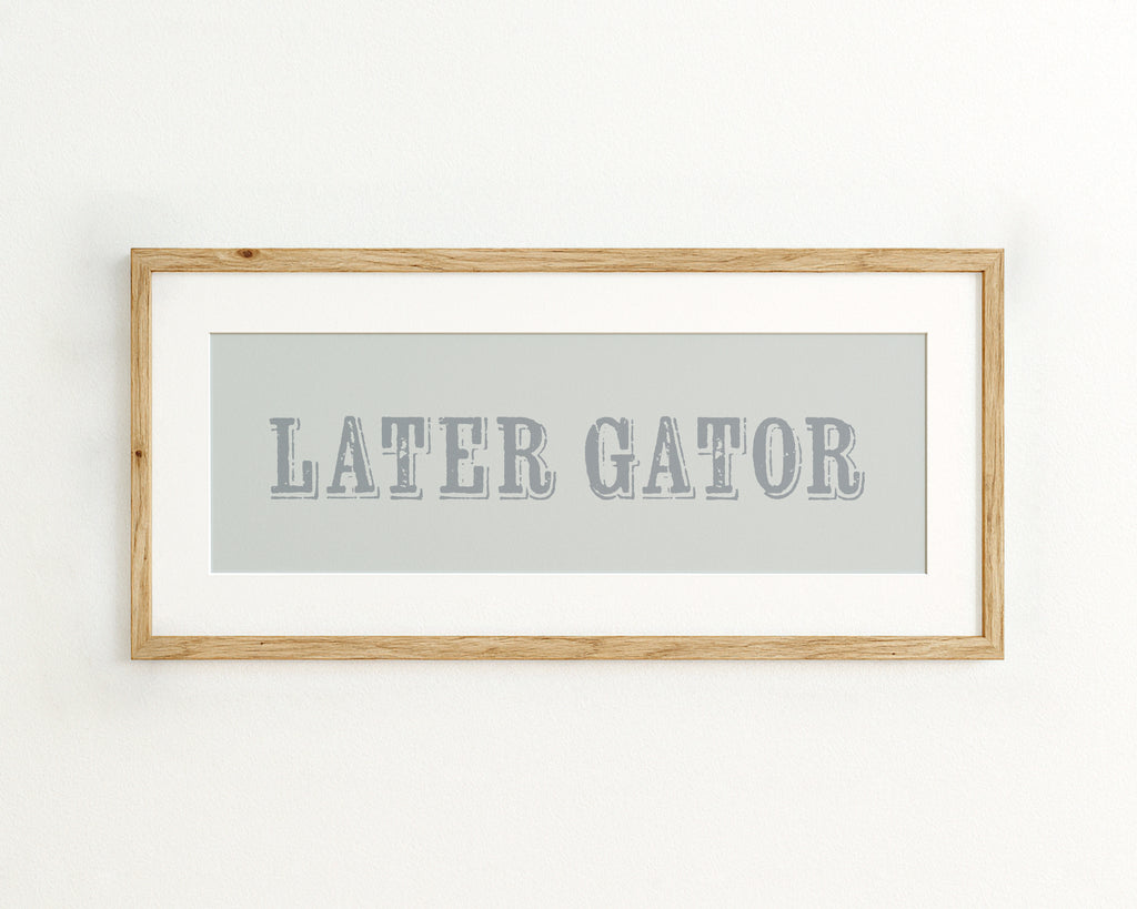 Framed artwork with 'LATER GATOR' text on a light blue background