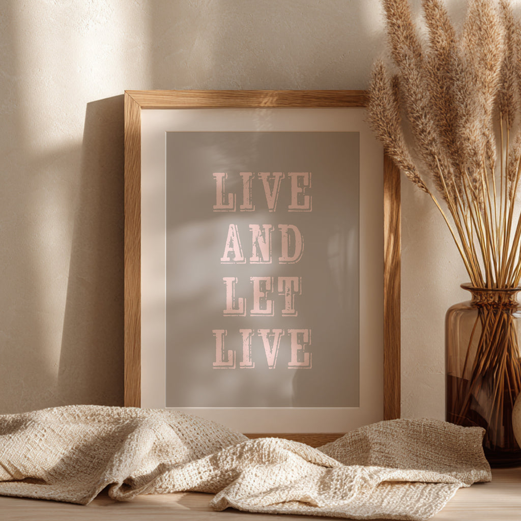Framed art print with the phrase 'Live and Let Live' leaning against a wall on a sideboard