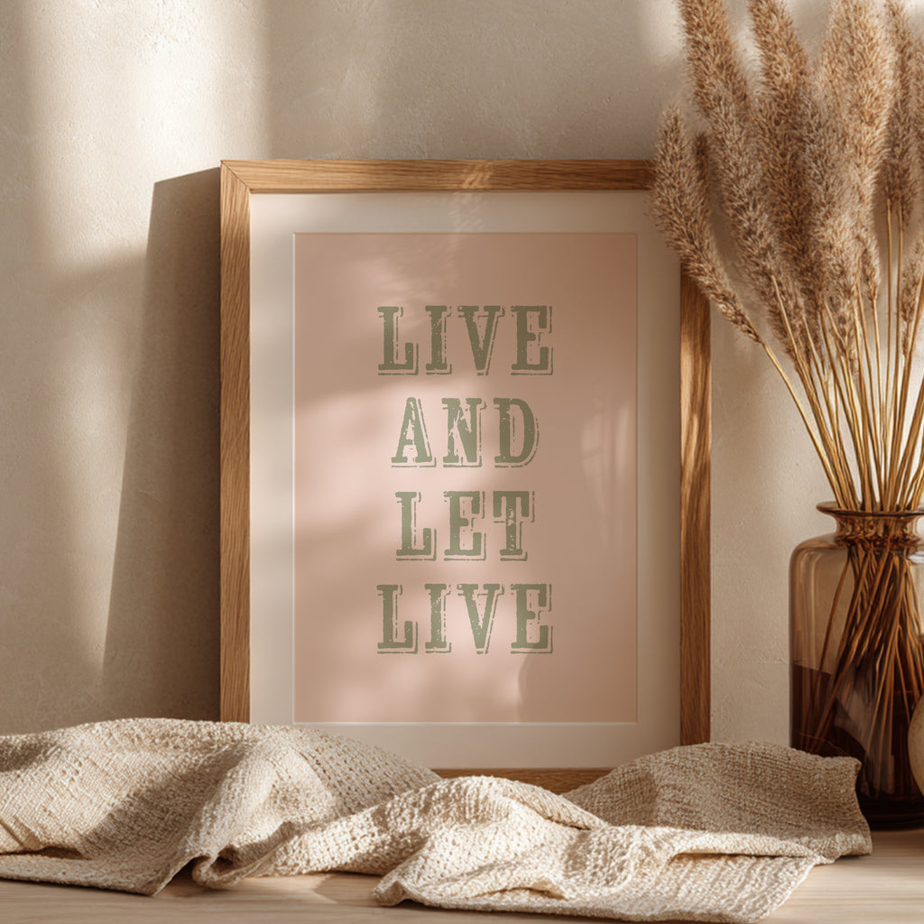 Framed art print with the phrase 'Live and Let Live' leaning against a wall on a sideboard