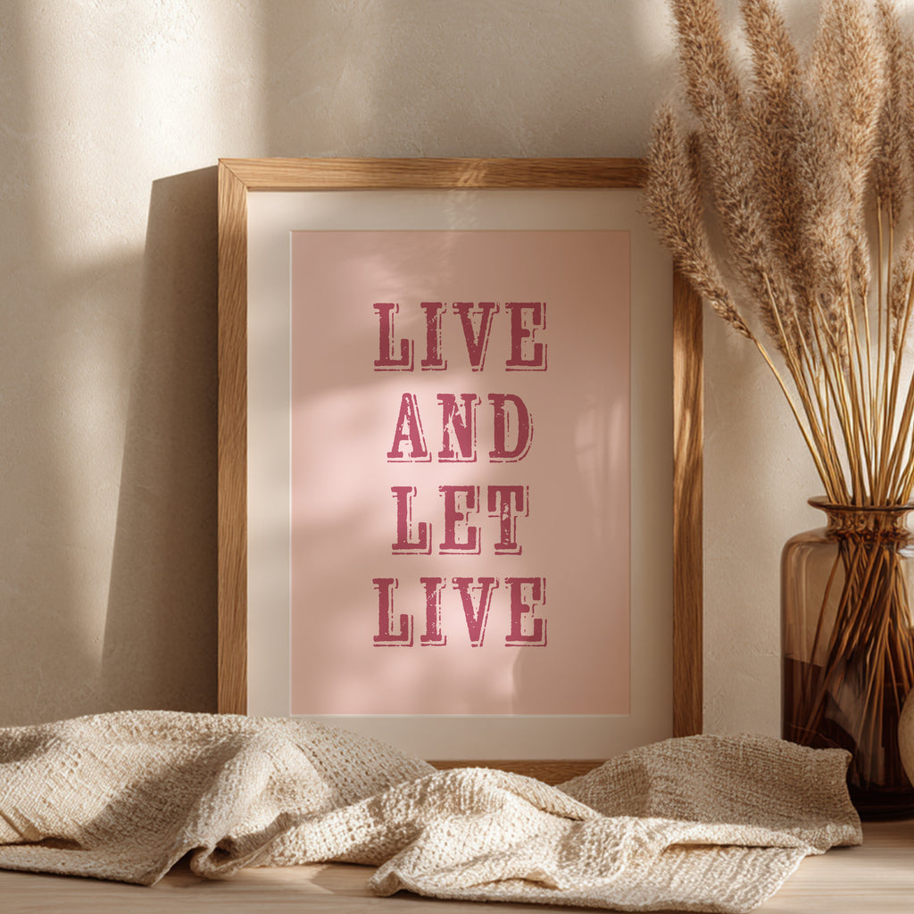 Framed art print with the phrase 'Live and Let Live' leaning against a wall on a sideboard