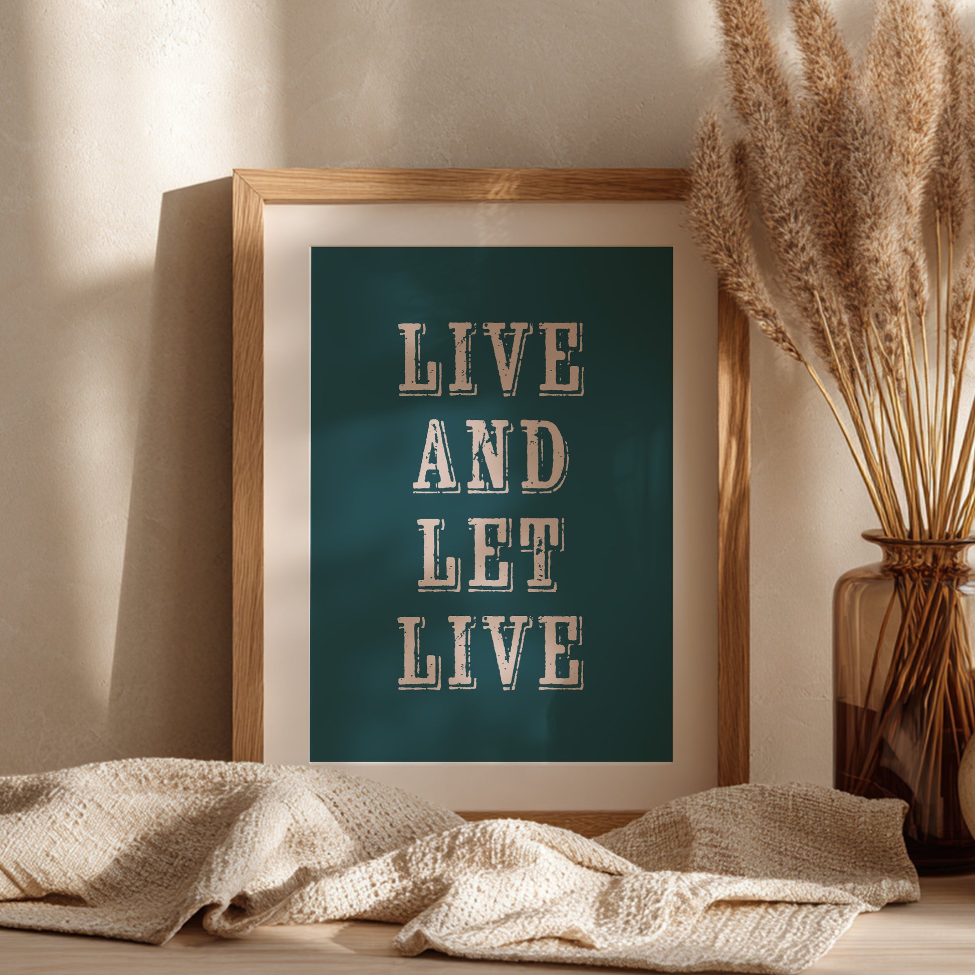 Framed art print with the phrase 'Live and Let Live' leaning against a wall on a sideboard