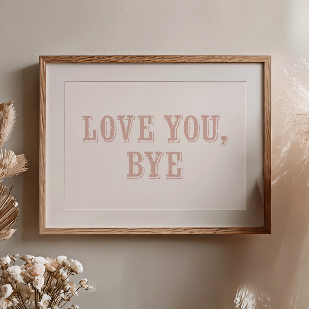 Framed artwork with 'LOVE YOU, BYE' text on a neutral wall with decorative elements.