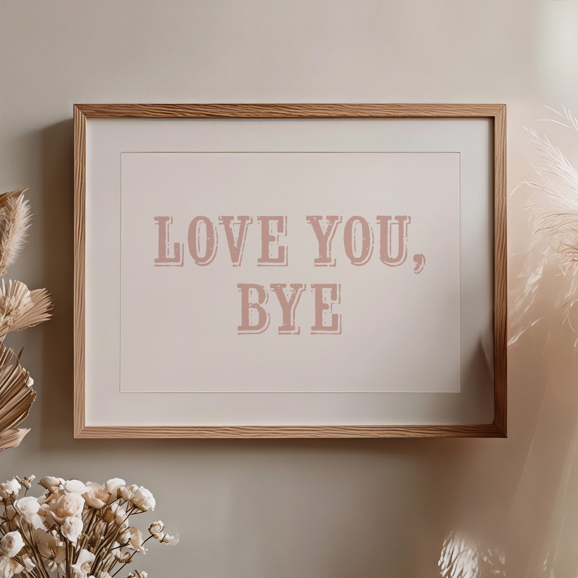 Framed artwork with 'LOVE YOU, BYE' text on a neutral wall with decorative elements.