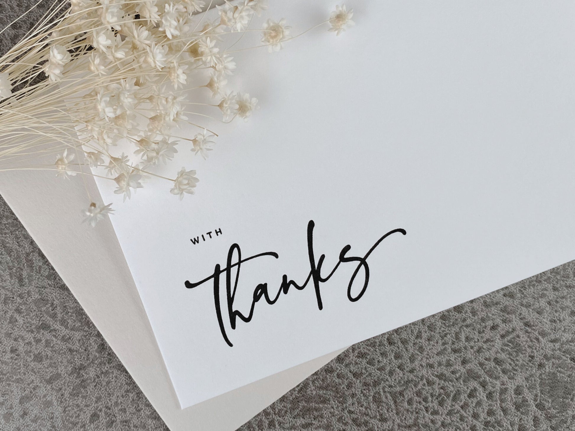 A white letterpress greeting card with the phrase 'With Thanks' printed in black, accompanied by a premium envelope.