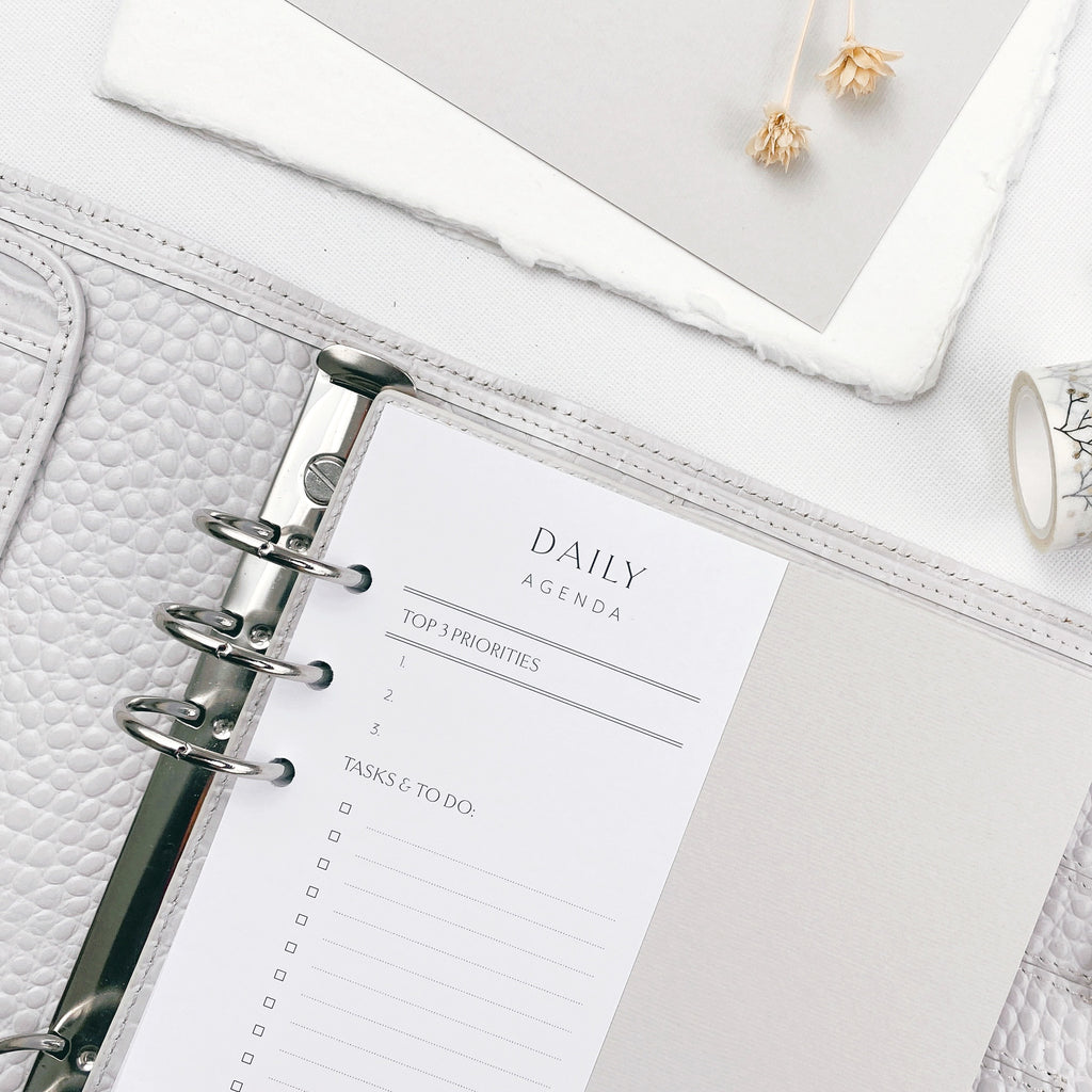 Slimline daily agenda planner insert in a grey agenda on a white surface with decorative elements