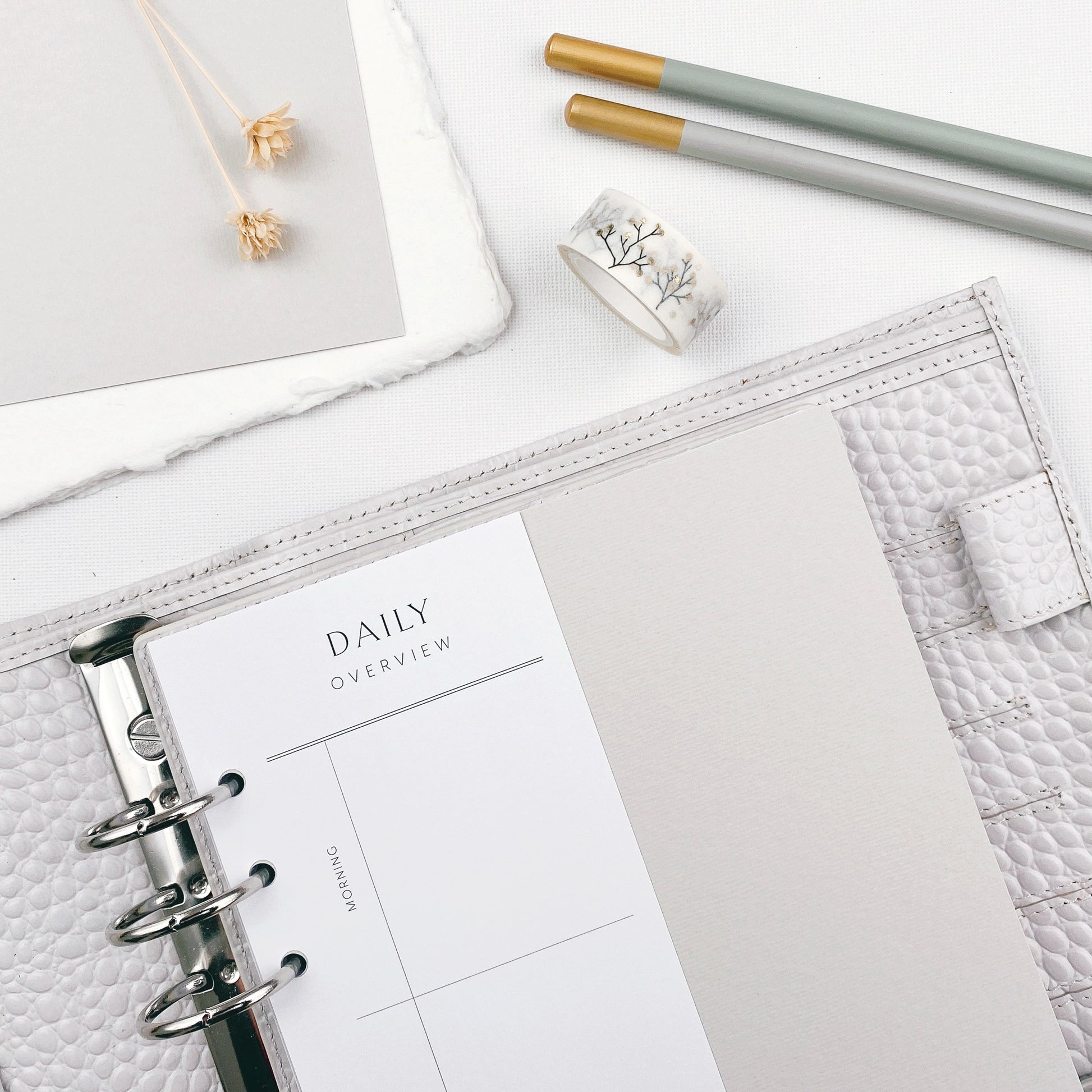 Planner with 'Daily Overview' page on a white surface with stationery items.