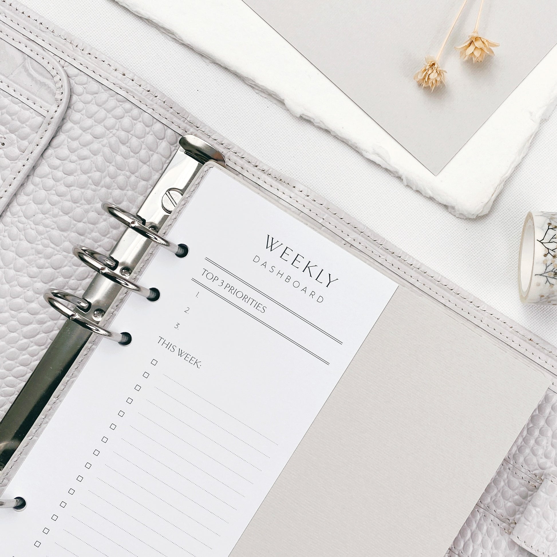 Weekly dashboard planner sheet in a ring binder on a white surface