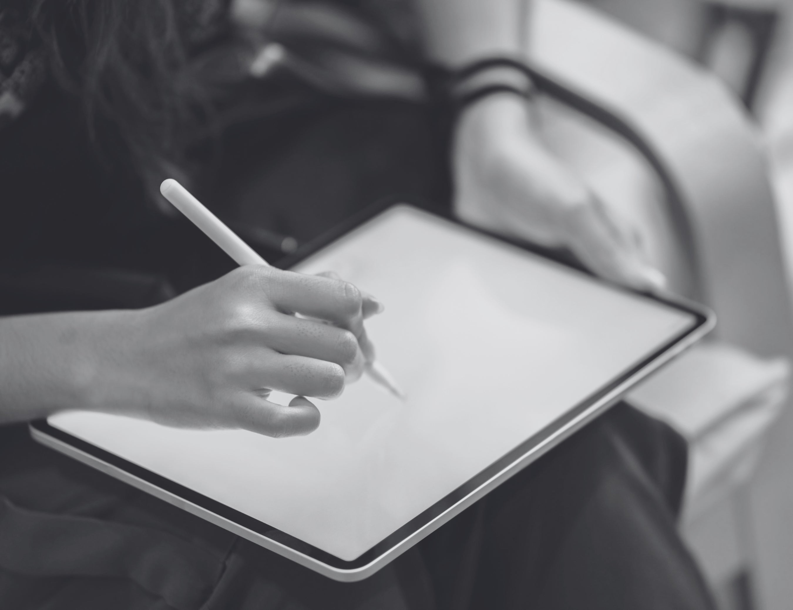 Person using a stylus on a digital tablet with a blurred background