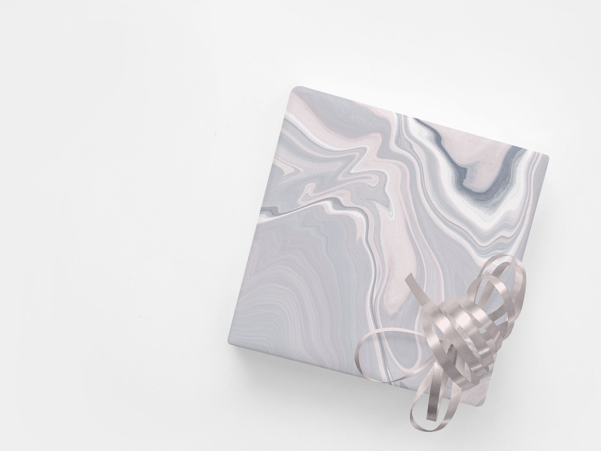 A gift wrapped with paper featuring an abstract marble pattern in pink and grey tones.
