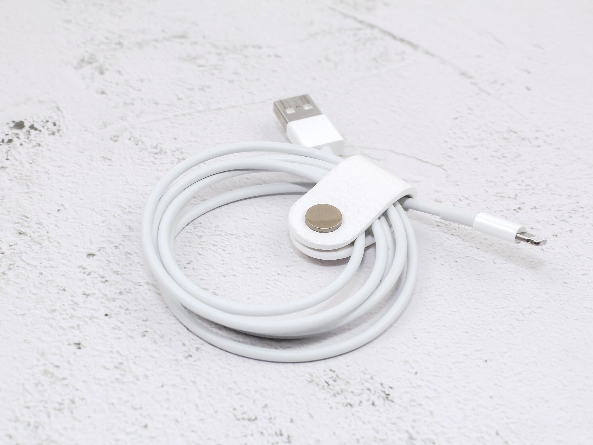 A white cord wrap in pebble-grain faux leather against a textured background