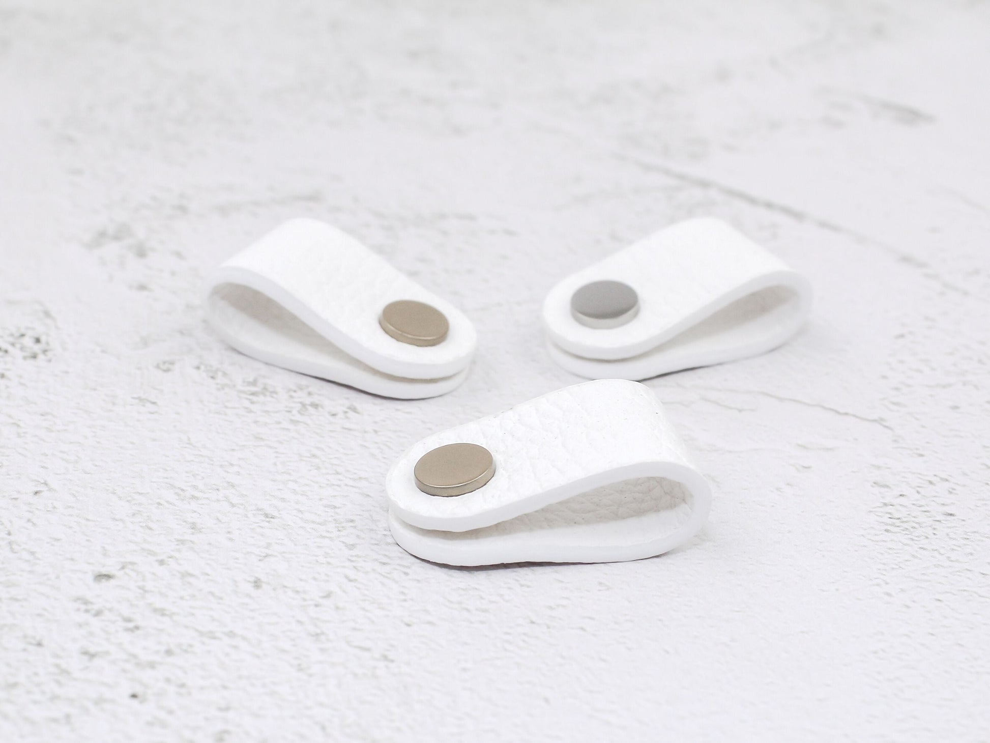 Set of 3 white pebbled-grain faux leather cord wraps with a snap closure, displayed on a textured background.