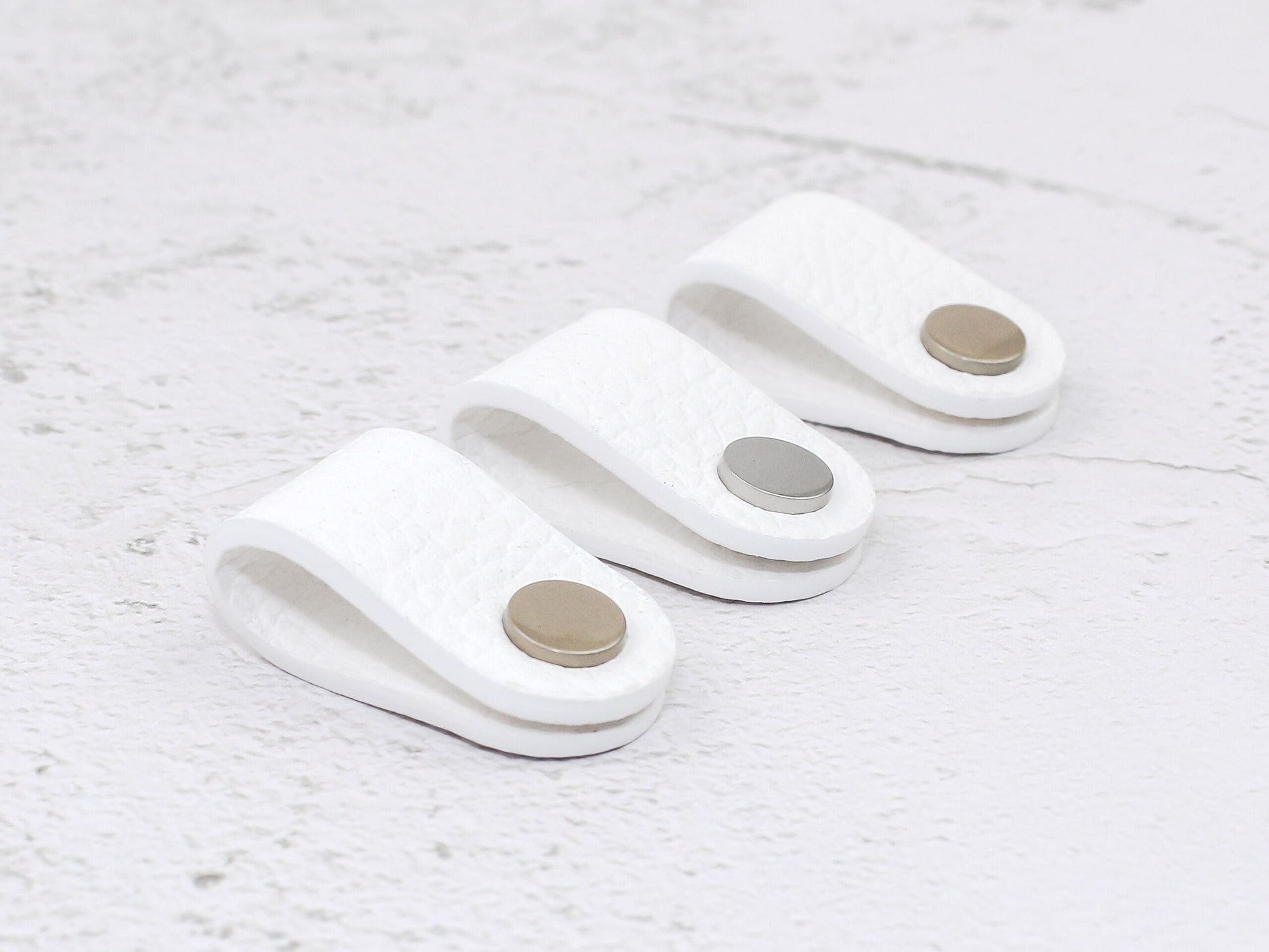 Set of 3 white pebbled-grain faux leather cord wraps with a snap closure, displayed on a textured background.